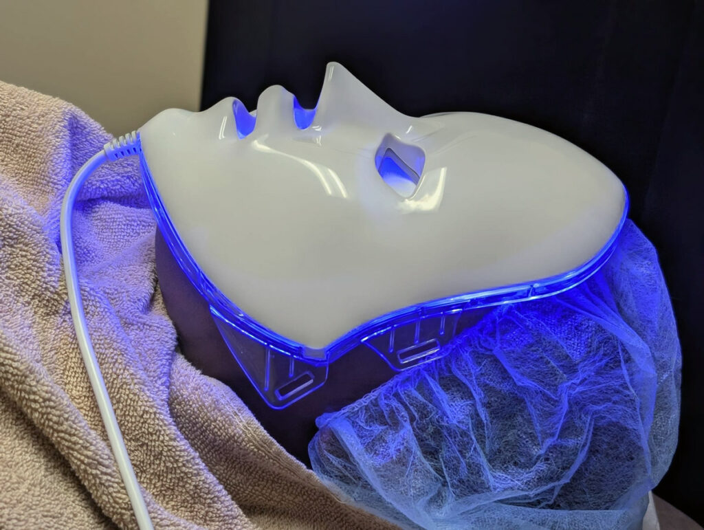 Patient receiving blue LED light therapy treatment at Clare Dermatology using a professional LED face mask